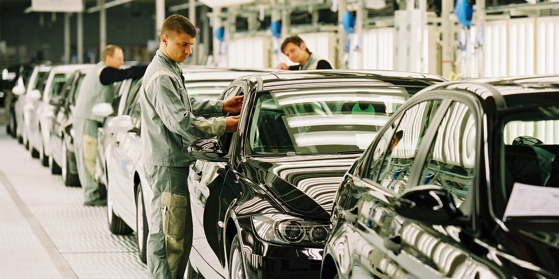 BMW-Werk Leipzig: Ein Arbeiter montiert an einem schwarzen BMW, dahinter stehen weitere Fahrzeuge auf der Produktionslinie